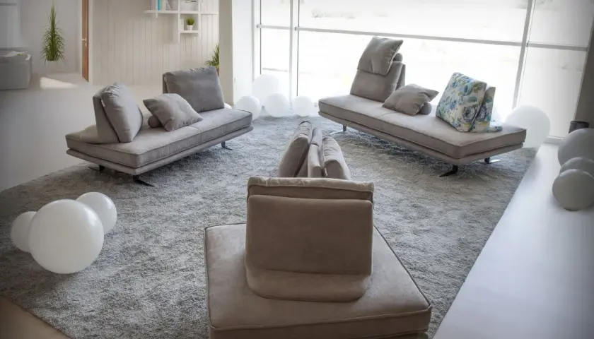 Salon moderne avec un canapé designer connu, des coussins moelleux et des ballons blancs sur un tapis épais.
