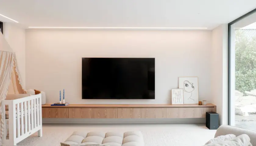 Un meuble TV suspendu, épuré et en bois, avec une télévision et des décorations. Idéal pour un salon moderne.