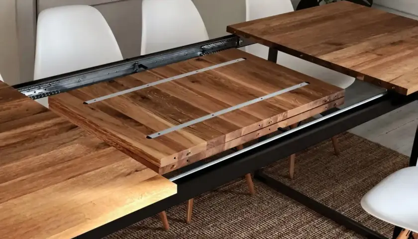 Détail du système de rallonge de table en bois, montrant les coulisses métalliques et les extensions empilées.