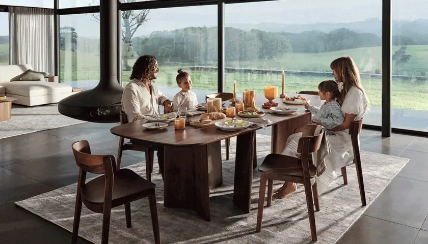 Une famille partage un repas autour d'une table à manger en bois. La hauteur de la table est parfaite pour la vue panoramique sur la campagne.