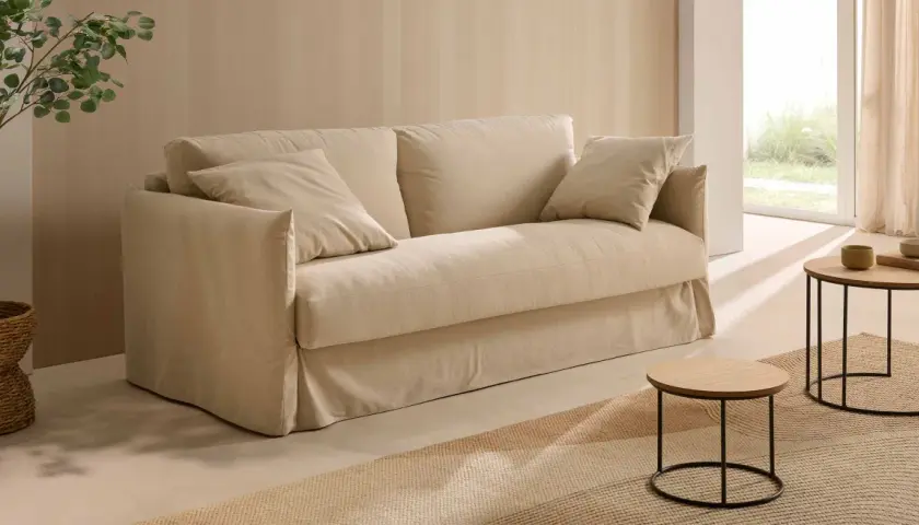 Un canapé beige confortable, des coussins douillets, une plante verte et des tables basses en bois. Quelle déco avec canapé beige pour un salon cosy et lumineux.