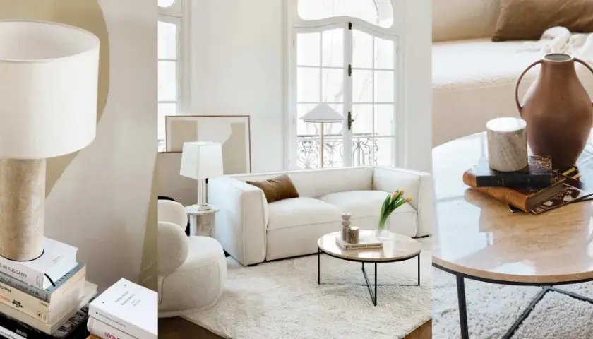 Un salon sans meuble TV, avec un canapé blanc, des lampes, des livres et une table basse en marbre.