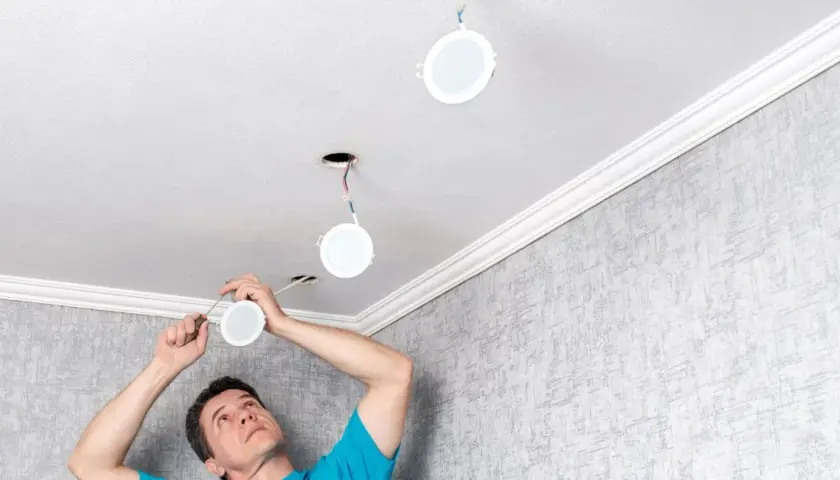 Installation d'un spot LED 220V sans transformateur. Un homme installe des luminaires ronds au plafond.