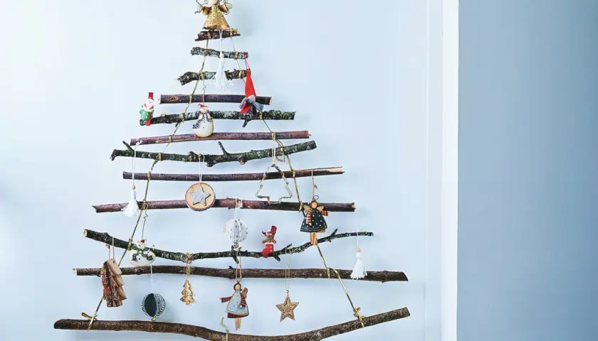 Arbre de Noël original à fabriquer soi-même avec des branches de récupération. Décoré de petites figurines et ornements suspendus.