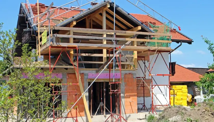 Une maison en pleine rénovation, avec échafaudages et matériaux de construction. Les propriétaires sont occupés à faire des travaux dans leur maison.