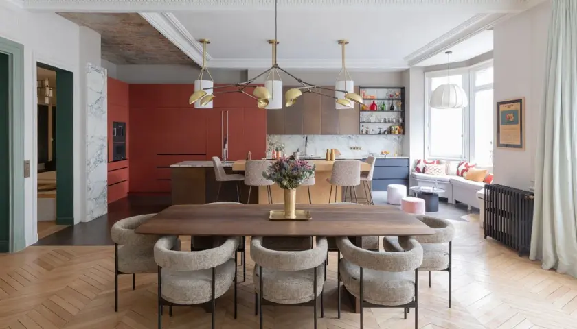 Un espace de vie salle à manger moderne avec une table en bois, des chaises confortables et une cuisine aux armoires rouges vives.
