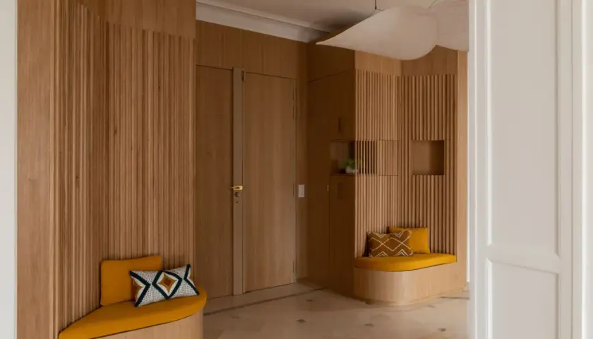 Élégante déco entrée maison en bois, avec banquettes confortables et coussins graphiques.