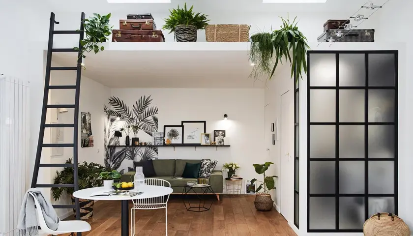 Aménagement intérieur appartement moderne avec mezzanine, échelle noire, mur végétal stylisé, mobilier design et verrière industrielle.