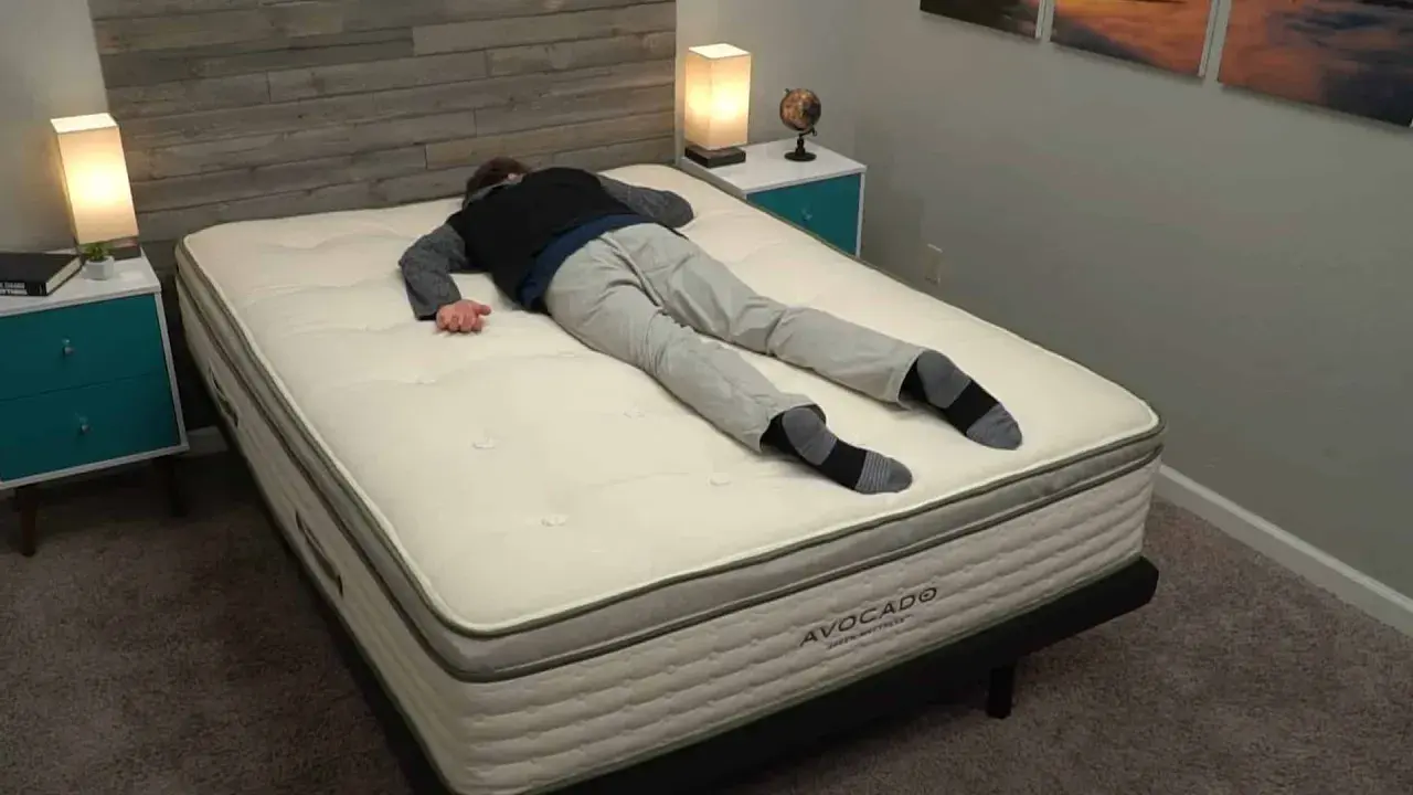 Un homme s'allonge sur le dos sur un matelas Avocado, idéal pour ceux qui aiment dormir sur le ventre.