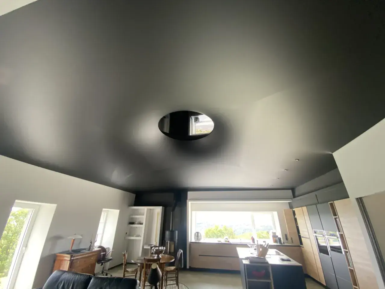 Plafond noir tendu, un cache-misère habile pour un plafond abîmé, avec une ouverture circulaire laissant apercevoir le ciel.
