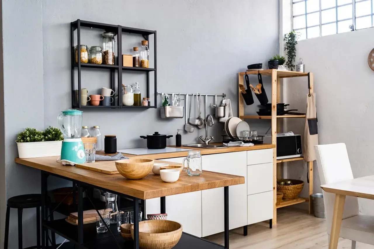 Une petite salle à manger moderne avec un îlot en bois, un mixeur turquoise et des étagères remplies d'ustensiles et d'épices.