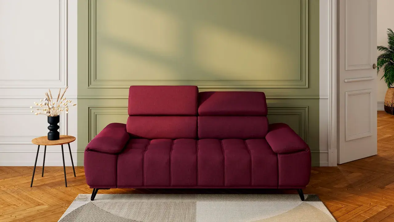 Un canapé rouge profond, avec un mur vert sauge derrière. Une table d'appoint en bois avec un vase noir et des herbes séchées. Quelle couleur associer avec un canapé rouge ?