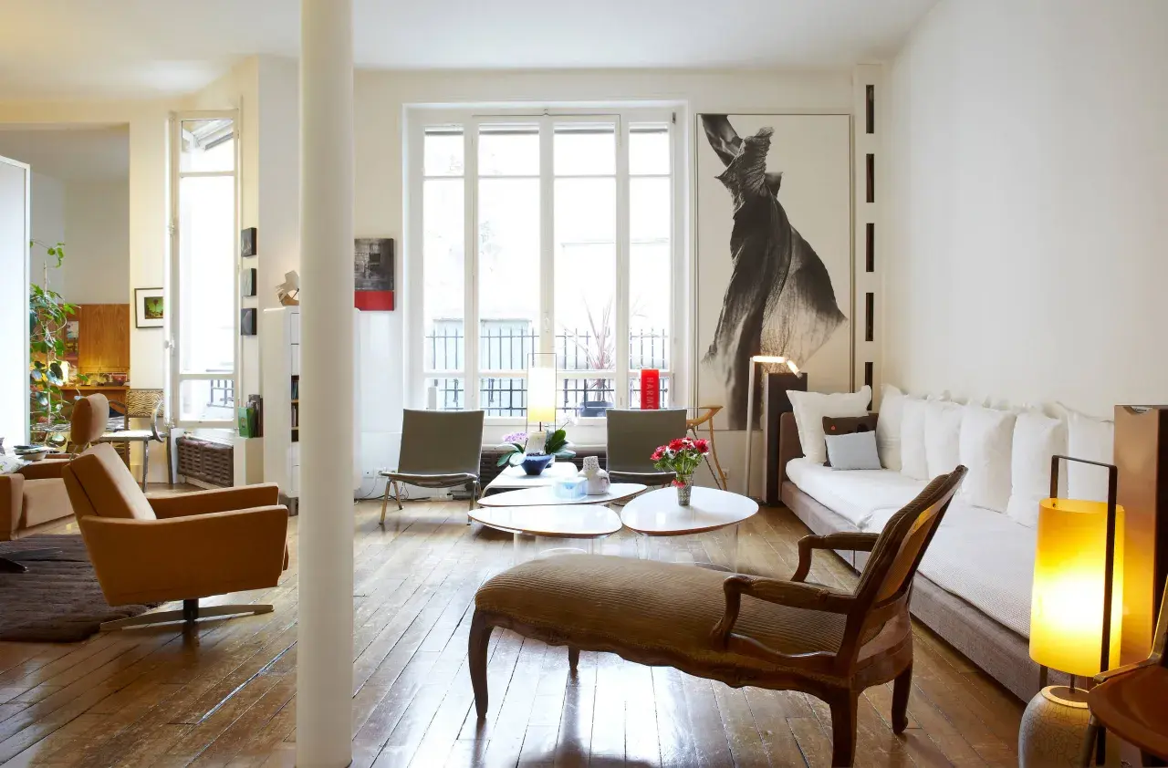 Salon lumineux avec des styles de meubles anciens, dont une méridienne en bois sculpté et des fauteuils en cuir.