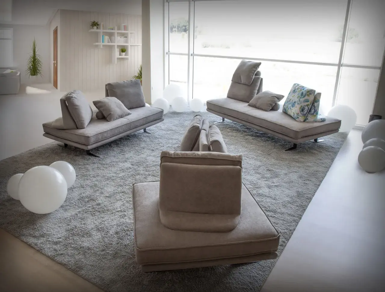 Salon moderne avec un canapé designer connu, des coussins moelleux et des ballons blancs sur un tapis épais.