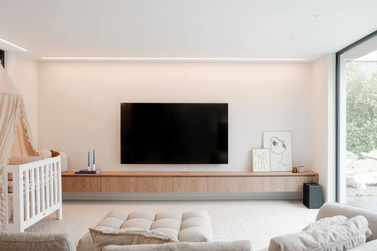 Un meuble TV suspendu, épuré et en bois, avec une télévision et des décorations. Idéal pour un salon moderne.