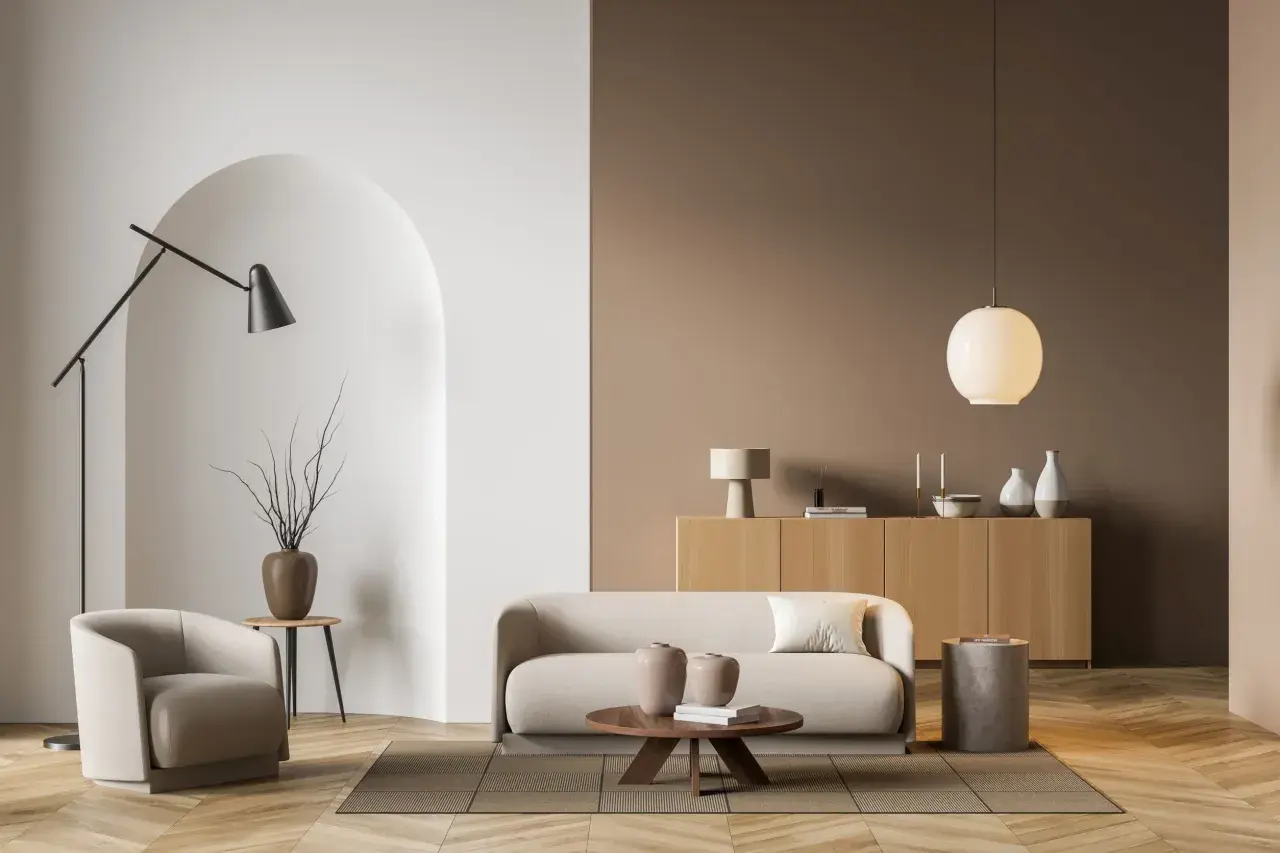 Salon moderne aux murs taupe couleur, avec un fauteuil, un canapé, une table basse et un buffet en bois clair.