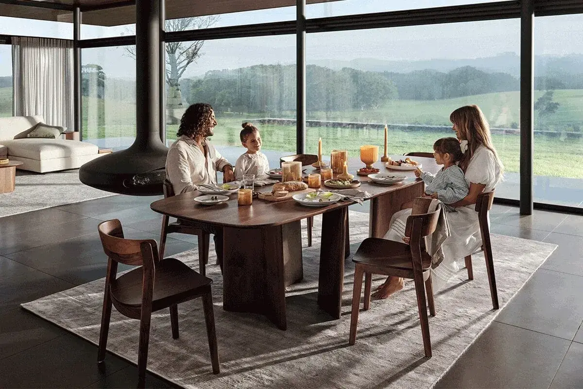 Une famille partage un repas autour d'une table à manger en bois. La hauteur de la table est parfaite pour la vue panoramique sur la campagne.