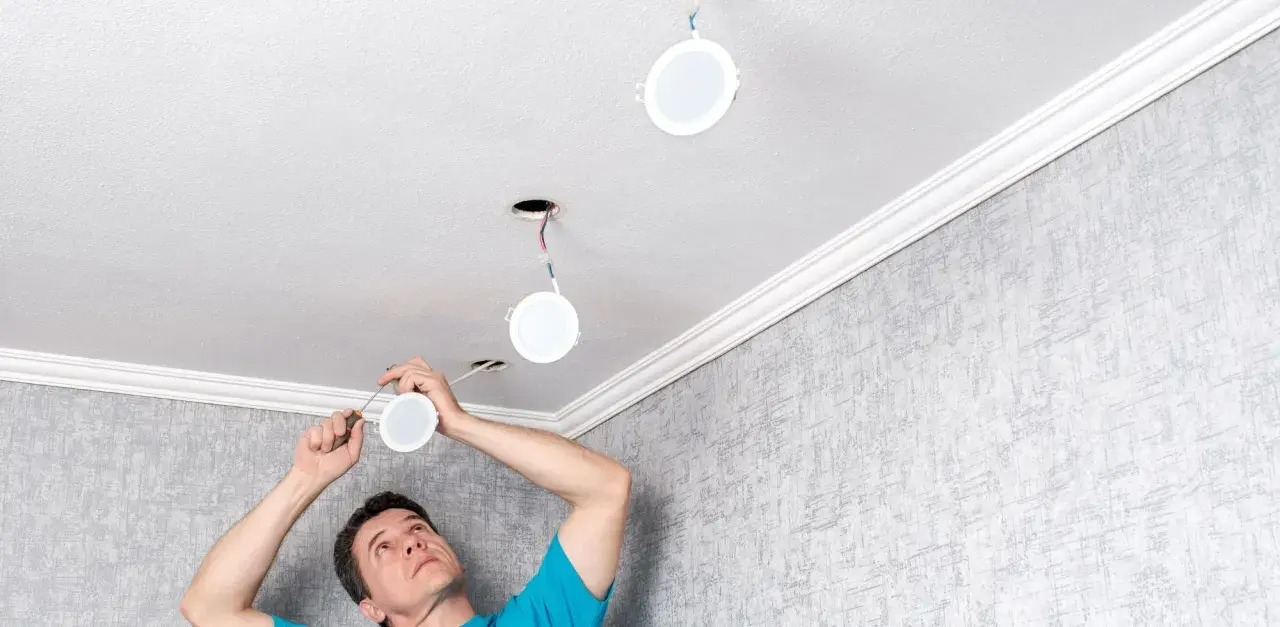 Installation d'un spot LED 220V sans transformateur. Un homme installe des luminaires ronds au plafond.