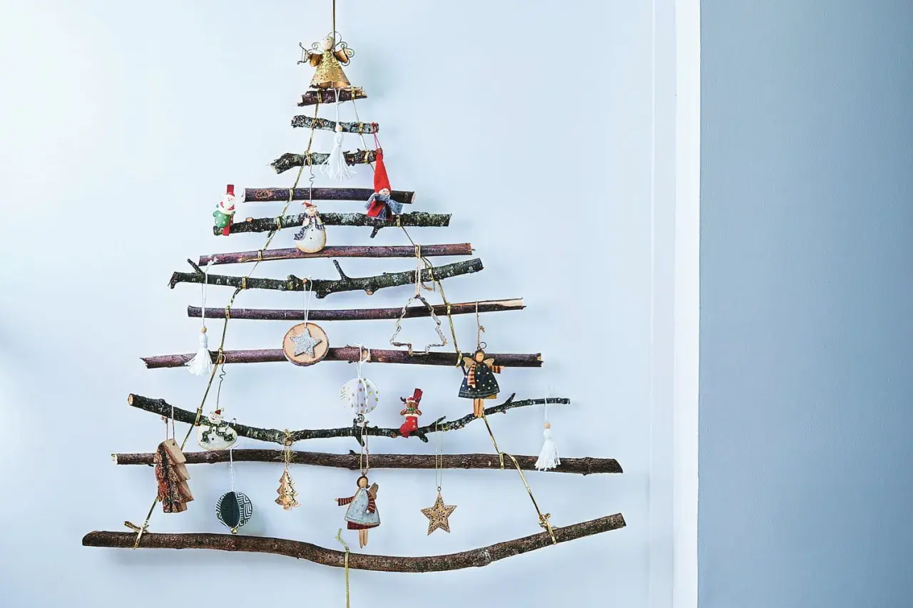 Arbre de Noël original à fabriquer soi-même avec des branches de récupération. Décoré de petites figurines et ornements suspendus.