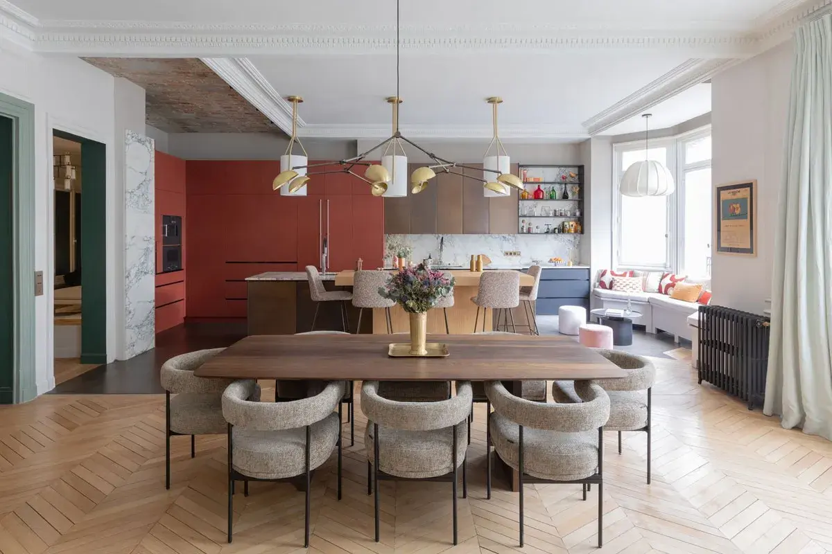 Un espace de vie salle à manger moderne avec une table en bois, des chaises confortables et une cuisine aux armoires rouges vives.