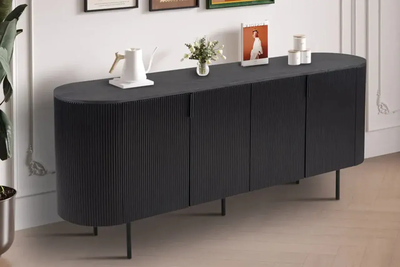 Buffet de salle à manger noir aux lignes verticales, avec une bouilloire blanche, des livres et des pots décoratifs sur le dessus. Ses dimensions s'intègrent parfaitement dans un espace moderne.