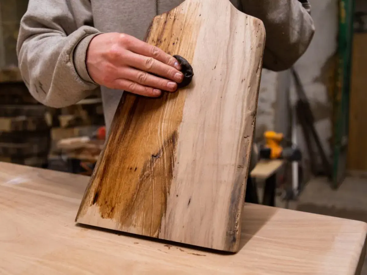 Application d'une solution pour le vieillir du bois, peut-être du bicarbonate de soude, sur une planche. La moitié gauche est foncée, l'autre est claire.
