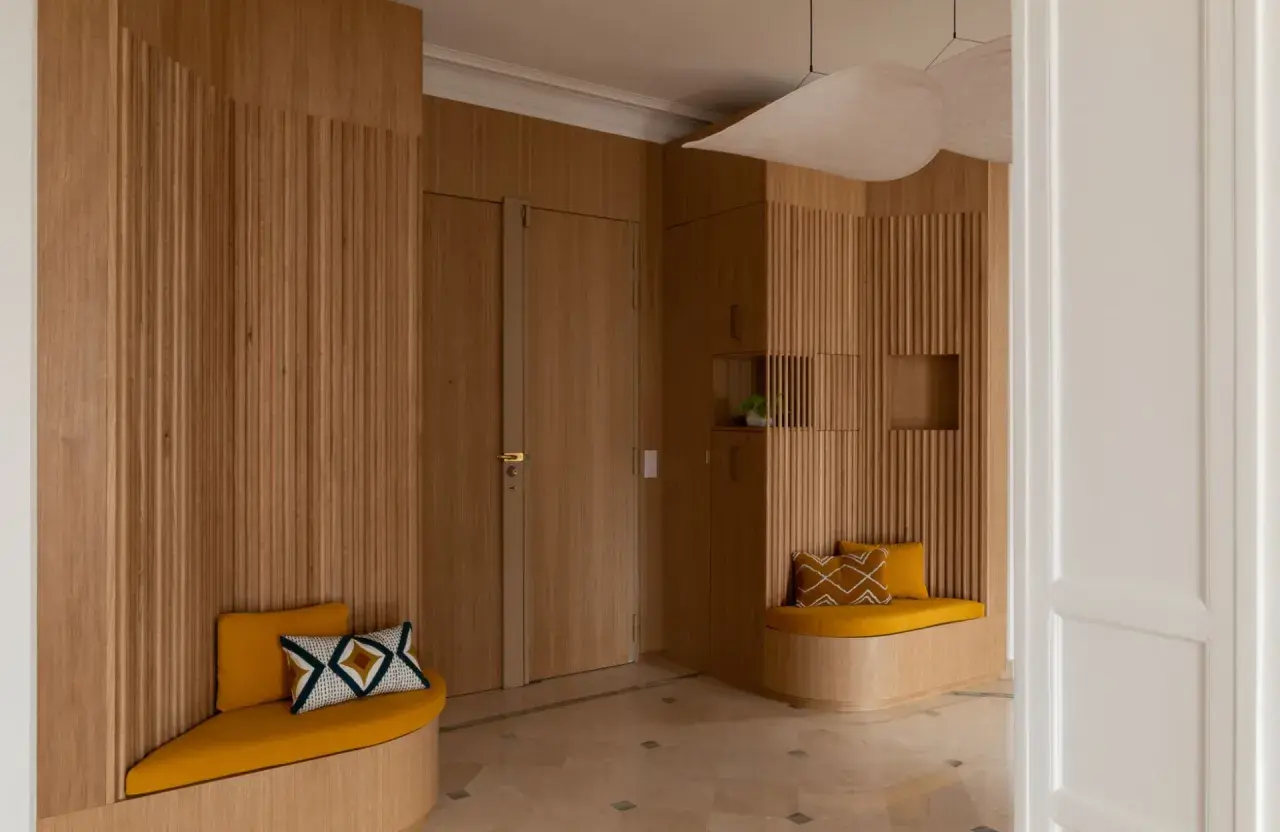 Élégante déco entrée maison en bois, avec banquettes confortables et coussins graphiques.