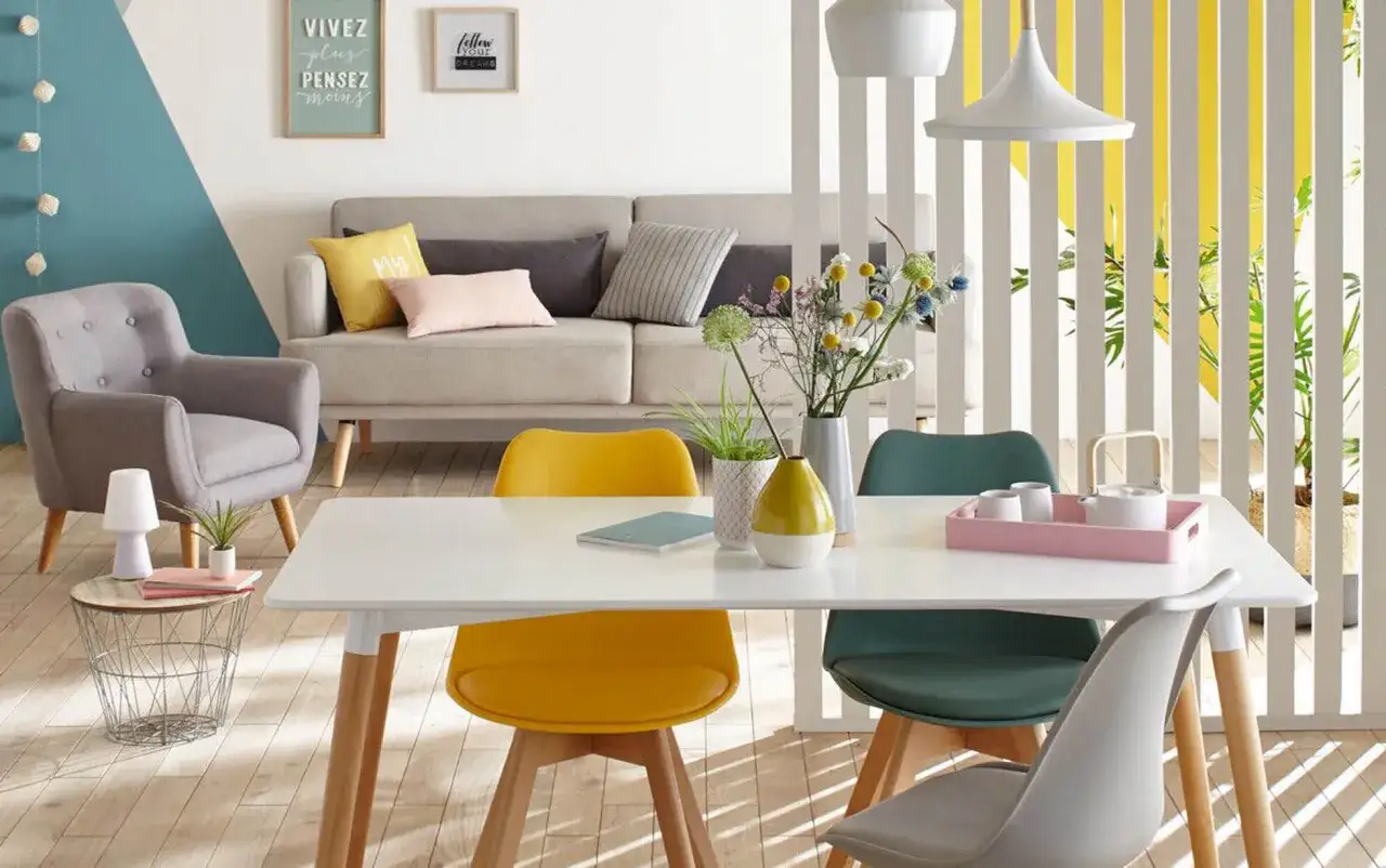 Id&eacute;es pour am&eacute;nager un petit salon : fauteuil gris, canap&eacute;, table blanche avec chaises color&eacute;es, d&eacute;co murale inspirante.