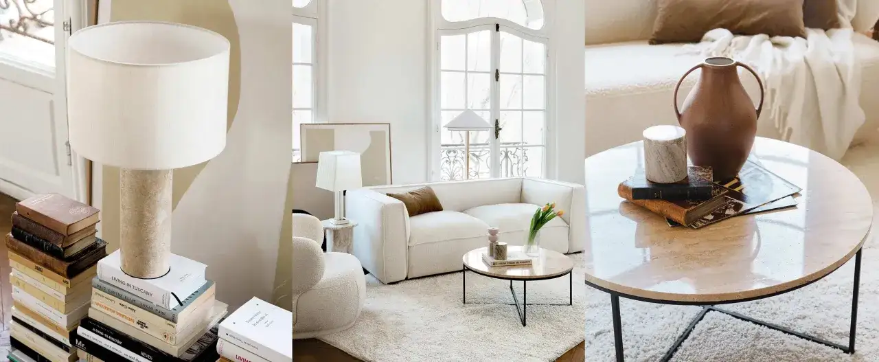 Un salon sans meuble TV, avec un canapé blanc, des lampes, des livres et une table basse en marbre.