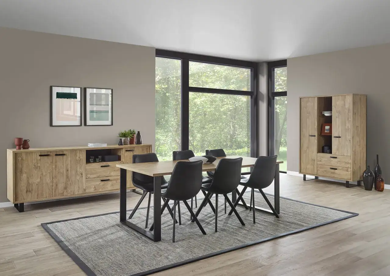 Une belle id&eacute;e d&eacute;co salle &agrave; manger industrielle : buffet en bois, table et chaises noires, et une grande fen&ecirc;tre offrant une vue sur la nature.