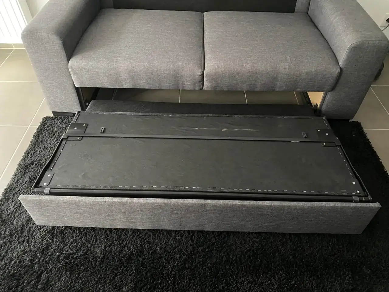 Le sommier d'un canap&eacute; convertible est sorti, pr&ecirc;t &agrave; &ecirc;tre remplac&eacute;.
