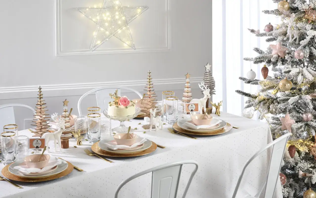 Une table de Noël élégante avec des rennes, des sapins en bois et une étoile lumineuse. Une belle idée décoration table noël.