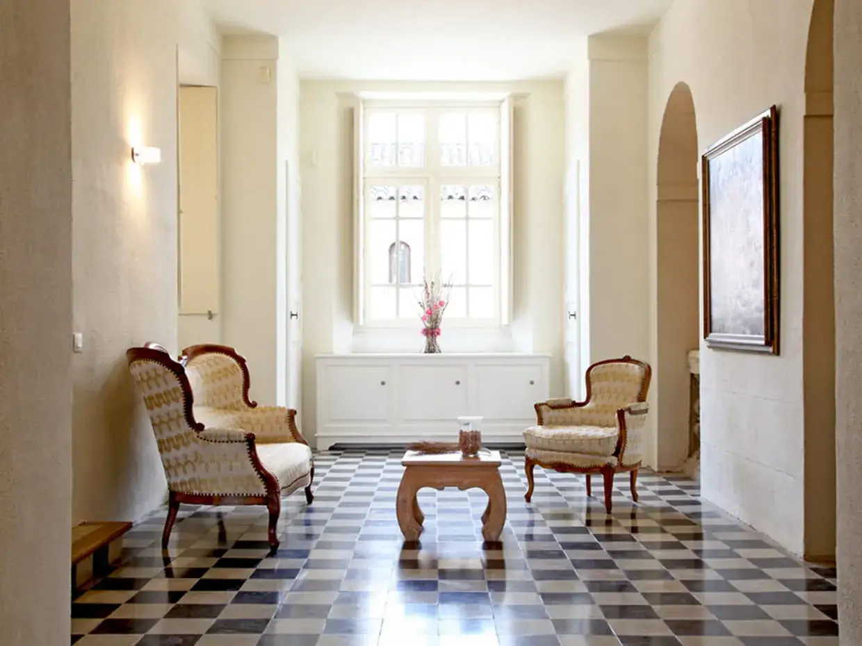 Un salon &eacute;l&eacute;gant o&ugrave; le style Louis-Philippe rencontre le contemporain. Deux fauteuils orn&eacute;s sont dispos&eacute;s autour d'une table basse en bois.