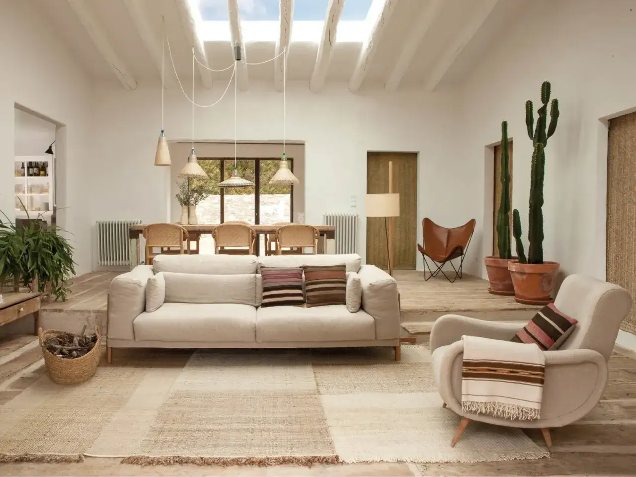 Quelle deco avec canape beige : salon lumineux avec canap&eacute; clair, fauteuil, cactus, table et chaises en rotin, tapis naturel.