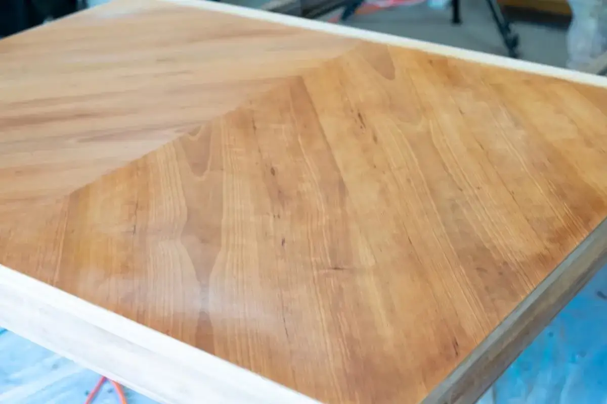 Application de bicarbonate de soude pour un vieillissement du bois. Le bois clair contraste avec la partie traitée, plus foncée.