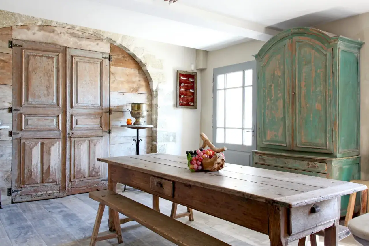 Table en bois brut, armoire verte patine bois effet vieilli, portes anciennes.
