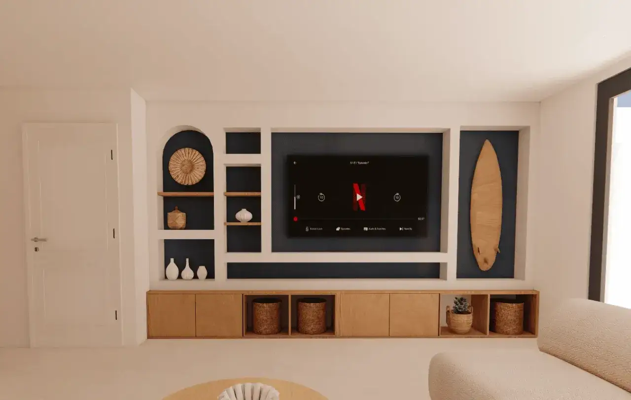 Une niche murale de salon TV avec une télévision, une planche de surf et des étagères décorées.