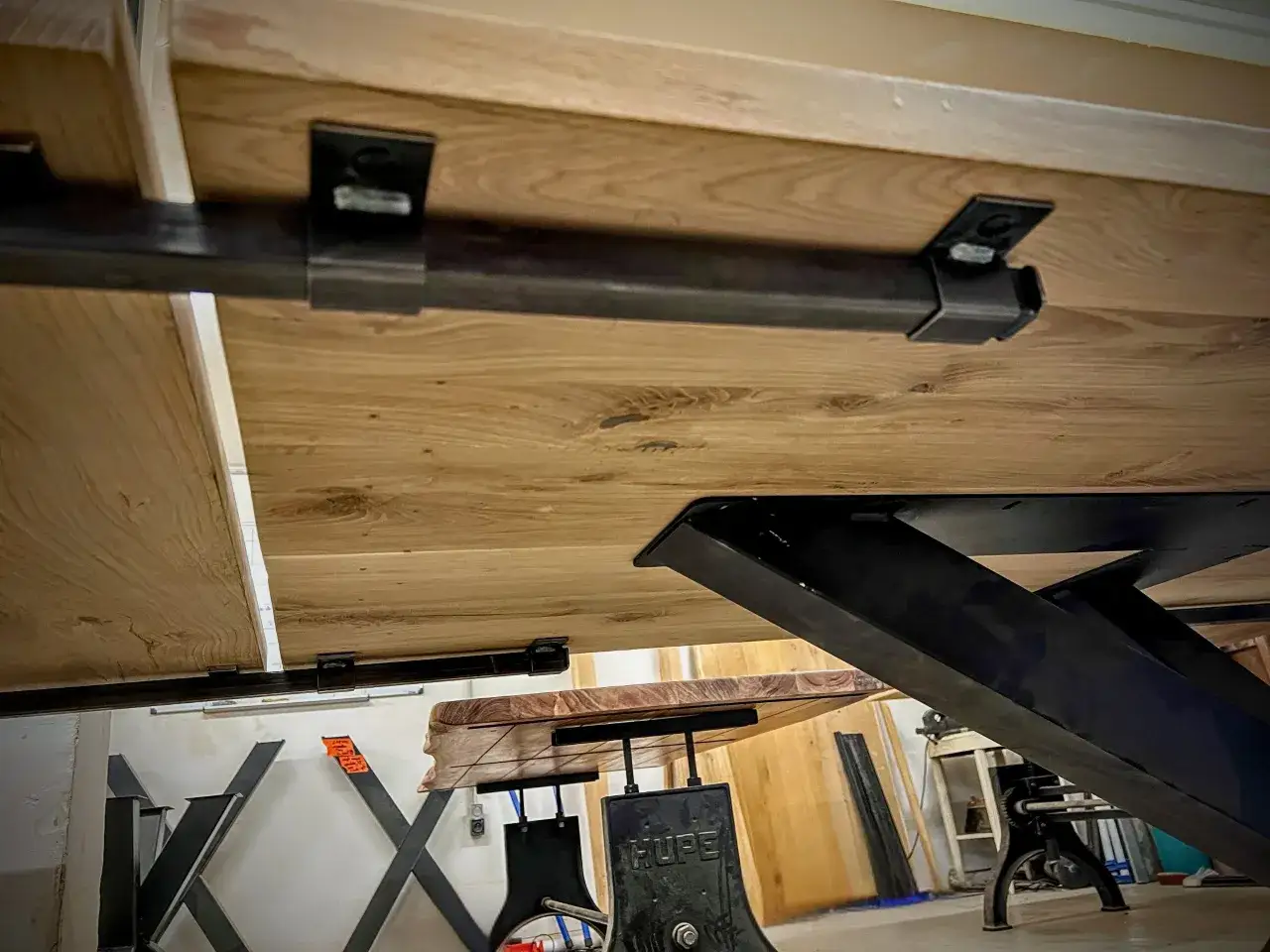 Vue du dessous d'une table en bois avec un système de rallonge de table métallique discret, prêt à agrandir l'espace.