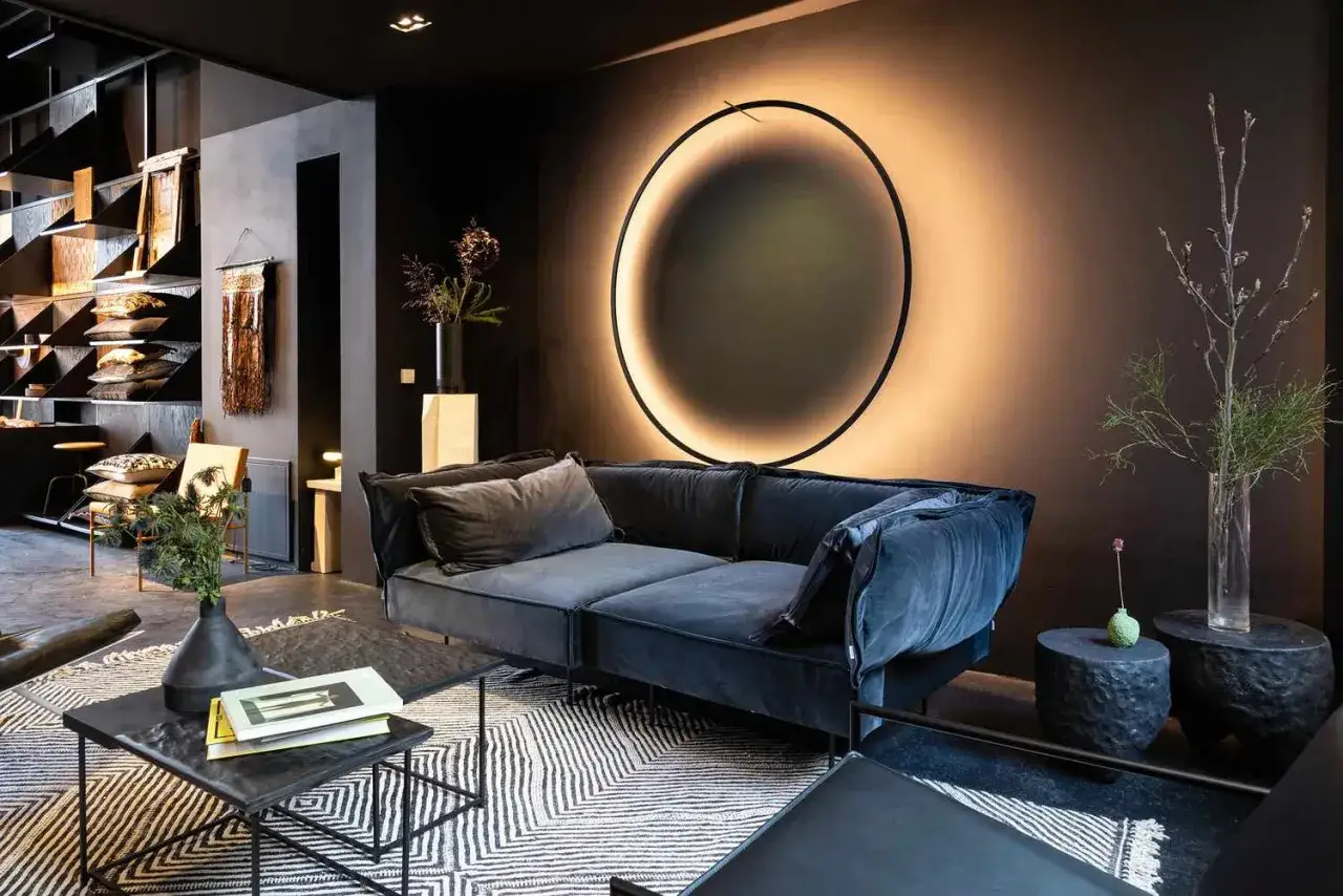 Salon moderne avec canap&eacute; bleu nuit, tapis graphique et une ampoule LED circulaire diffusant une douce lumi&egrave;re.