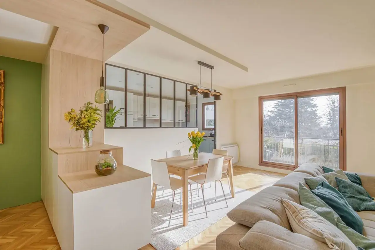 Am&eacute;nagement int&eacute;rieur appartement lumineux avec cuisine ouverte, salle &agrave; manger et salon. Bois clair, murs verts et blancs, grande baie vitr&eacute;e.