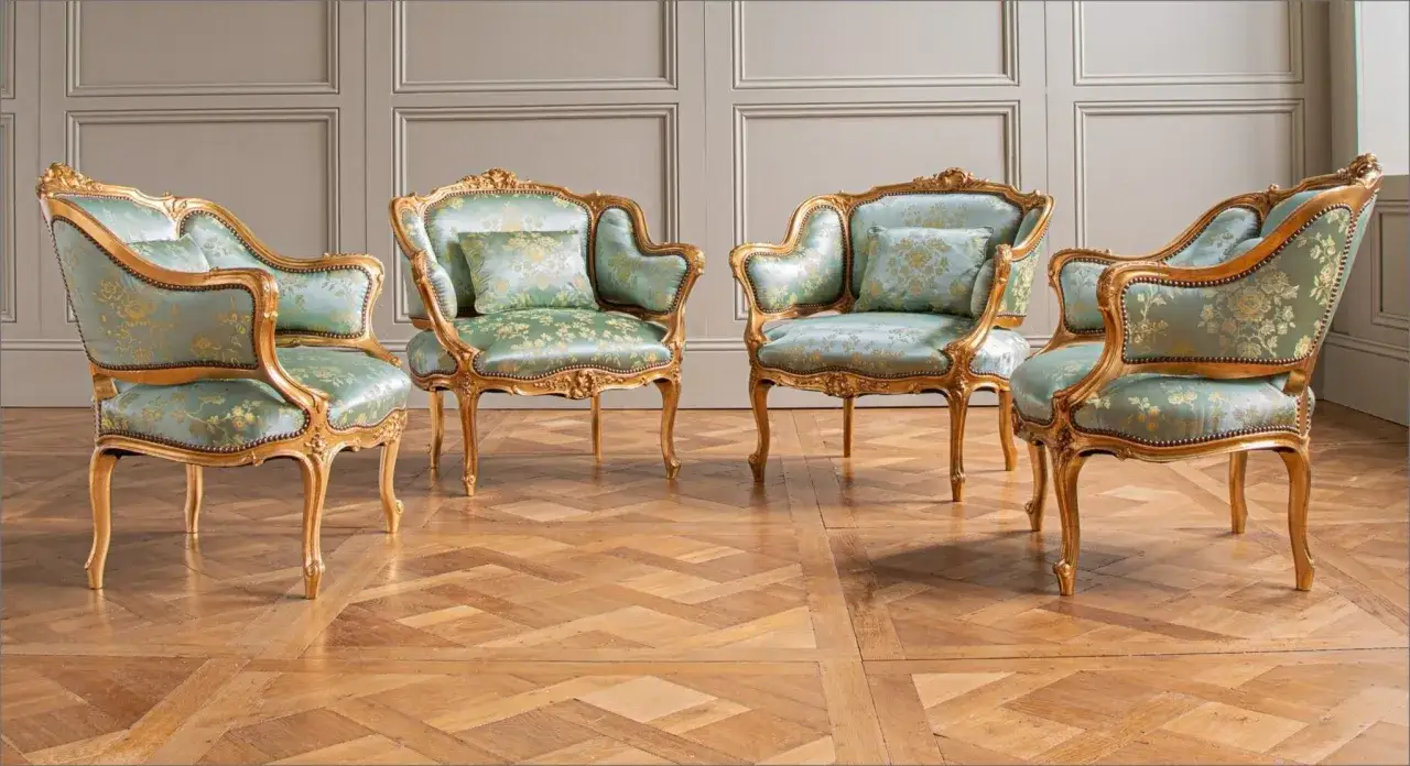Quatre fauteuils dorés aux motifs floraux bleu sarcelle, illustrant les styles de meubles anciens, sur un parquet en bois.