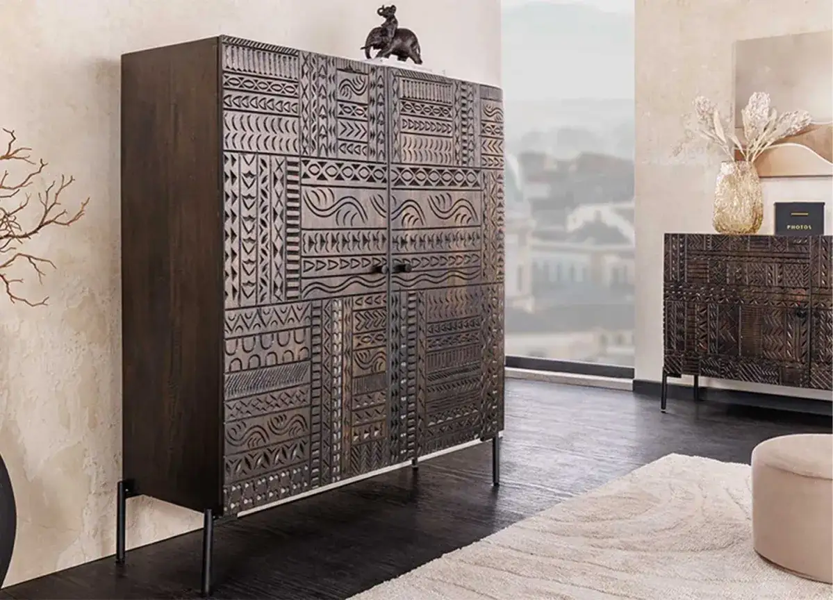 Buffet en bois sombre aux motifs ethniques sculpt&eacute;s, avec une figurine d'&eacute;l&eacute;phant sur le dessus. Sa hauteur est id&eacute;ale pour un salon.