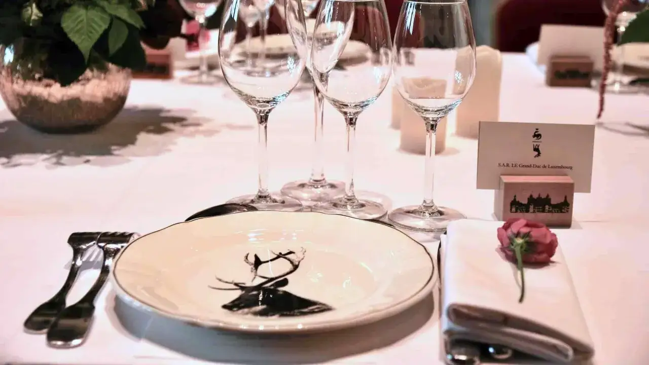 Mise en place d'un couvert de table &eacute;l&eacute;gant avec une assiette d&eacute;cor&eacute;e d'un cerf, des verres &agrave; pied et une rose sur une serviette.