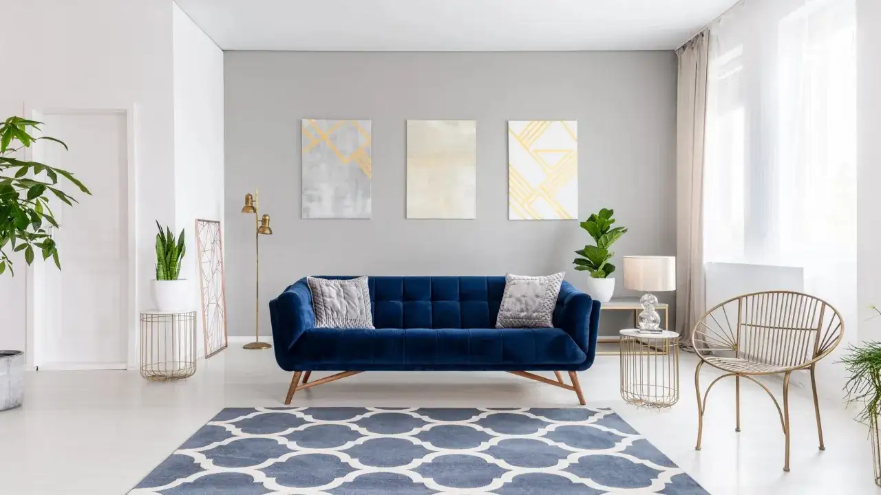 Salon moderne avec canap&eacute; bleu, tapis graphique et trois tableaux abstraits. Une touche de nature avec des plantes vertes et une ambiance saine gr&acirc;ce &agrave; une peinture sans solvant.